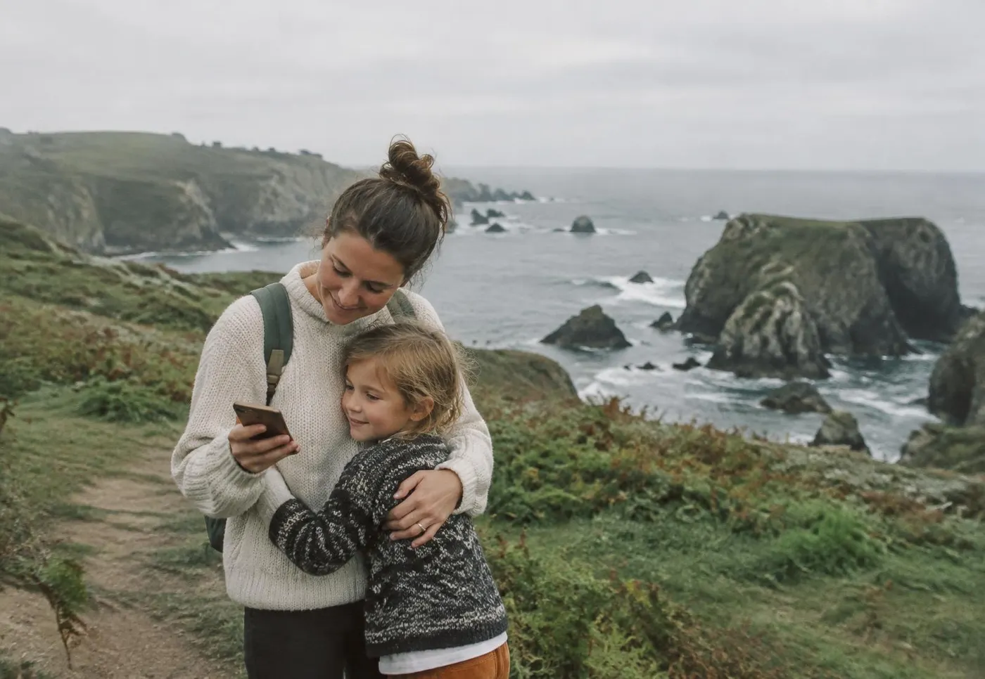 Mother and daughter on a coastal path looking at a phone